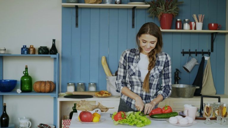 Cheerful young woman cooking breakfast in the kitchen early morning at home